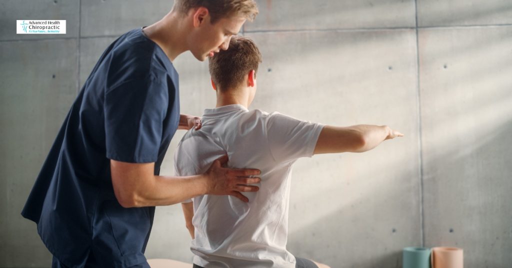 Person holding lower back in pain during chiropractic consultation