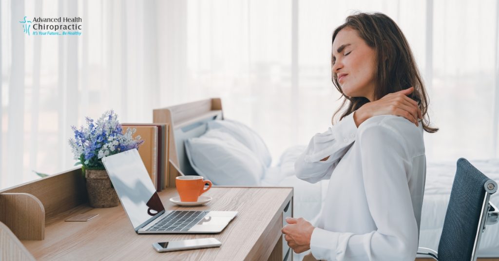 Person experiencing neck pain from poor posture at a computer desk.